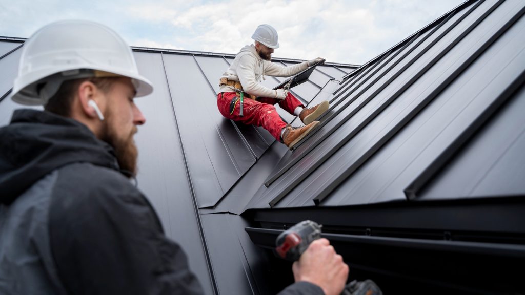 Roof installation work on a conservatory, with two workers in safety gear, one applying materials while the other assists, emphasizing energy-efficient upgrades.