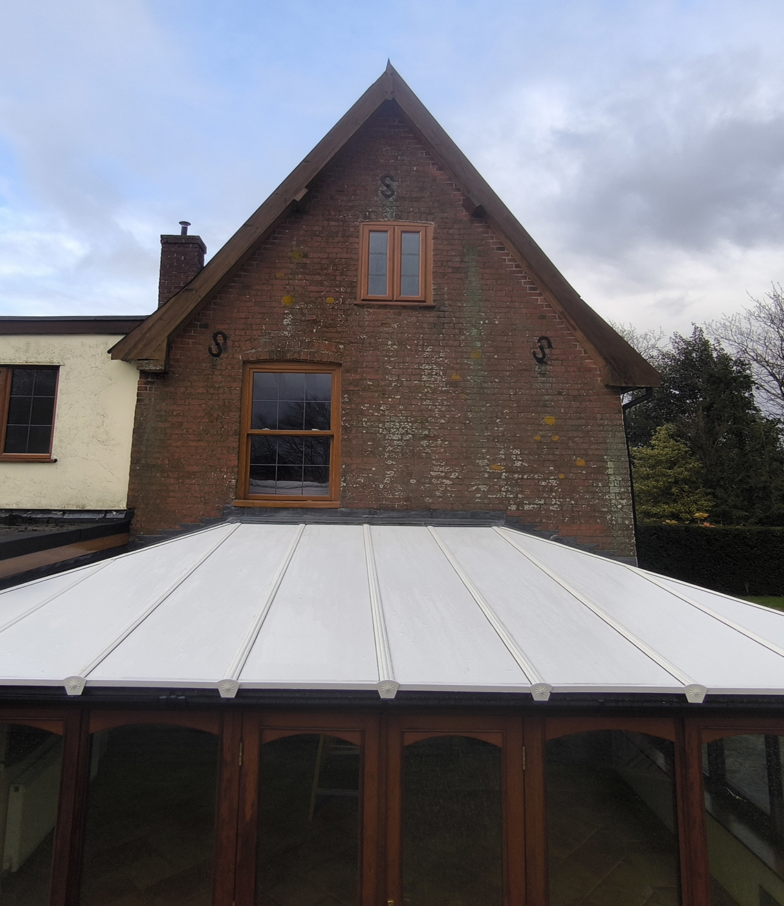 Insulated lean-to roof panels on a conservatory, showcasing a lightweight design and seamless integration with the existing structure, enhancing energy efficiency and aesthetic appeal.
