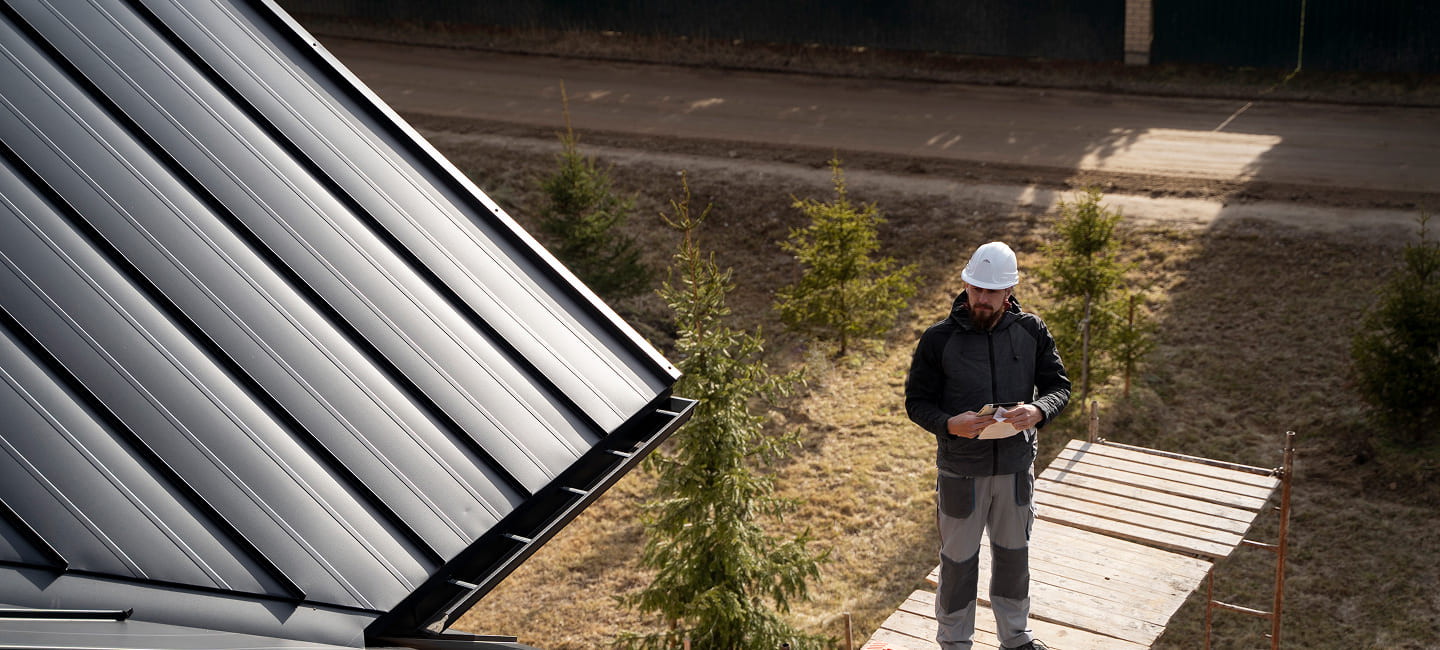 Man inspecting insulated roof panels on a conservatory, emphasizing energy efficiency and roofing solutions for reducing energy bills.