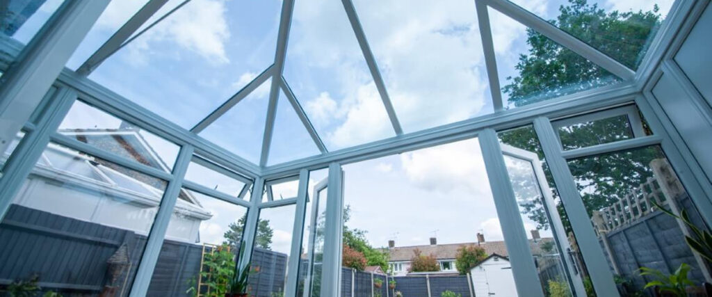 Interior view of a conservatory with a glass roof, showcasing natural light and garden views, emphasizing comfort and energy efficiency for year-round use.
