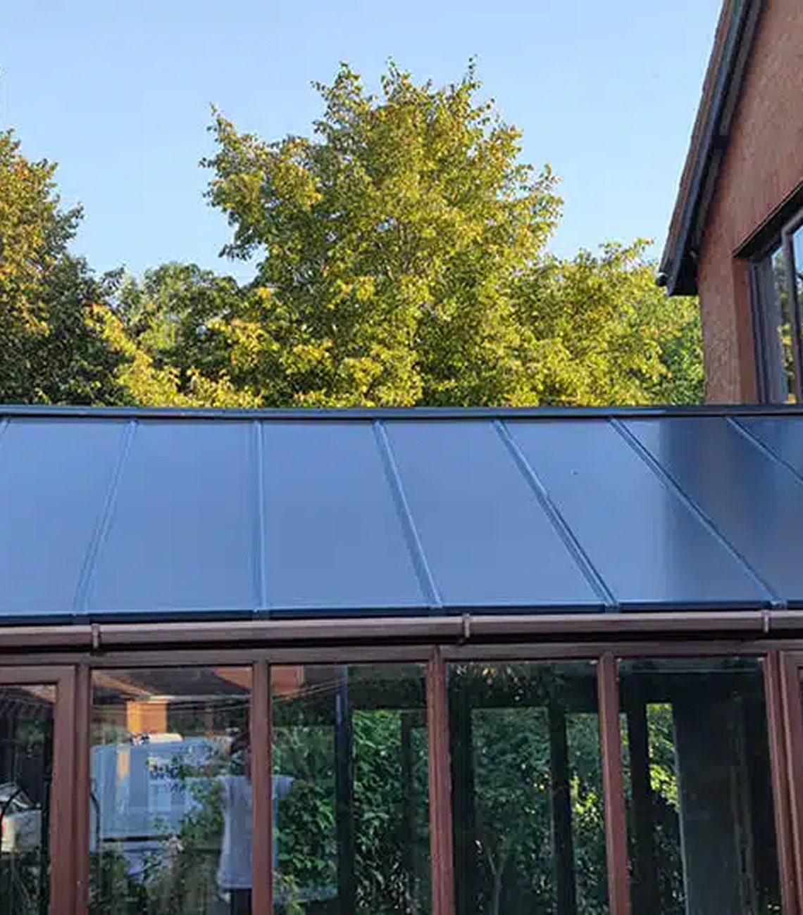 Conservatory roof with modern black panels and surrounding greenery, showcasing energy-efficient design for home improvement in Bournemouth.