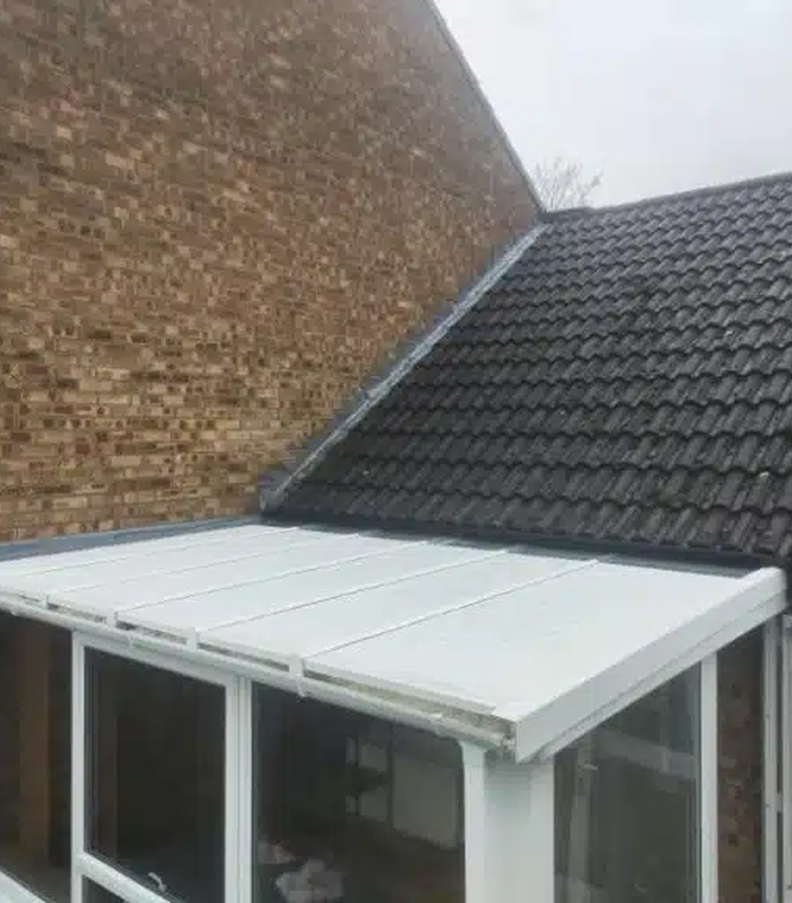 Conservatory roof replacement featuring insulated panels in Northampton, showcasing a modern design with a white finish and tiled roof elements.